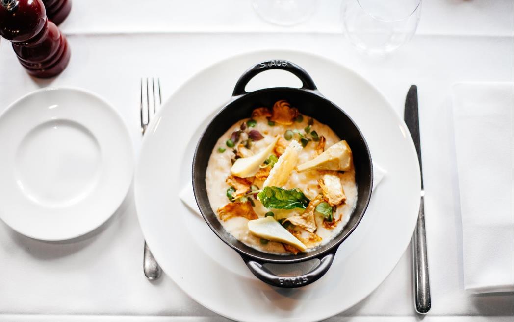 Dish served in a black pot on a table set with a white tablecloth.