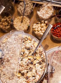 Diversi tipi di muesli, frutta secca e noci in piccole ciotole e contenitori.