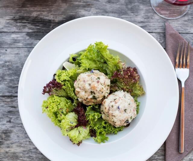 Two dumplings served on green salad on a white plate.
