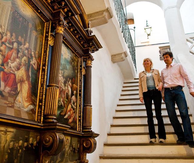 Zwei Personen auf der Treppe im Rathaus von Sterzing, neben einem historischen Gemälde.