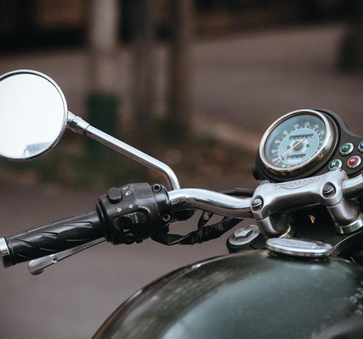 Nahaufnahme von Lenker, Rückspiegel und Tacho eines Motorrads.
