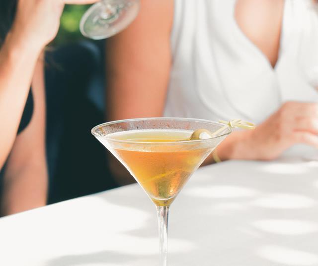 Close-up of an aperitif on a table with a white tablecloth; people are seated in front of it.