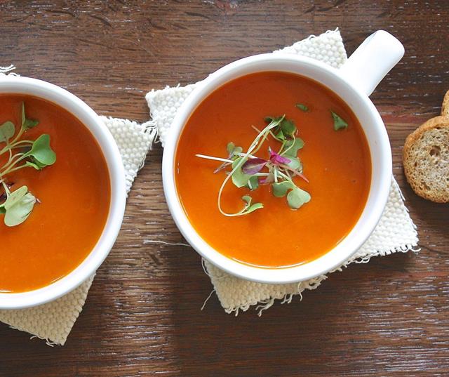 Due zuppe di pomodoro con crescione, servite in tazze bianche.