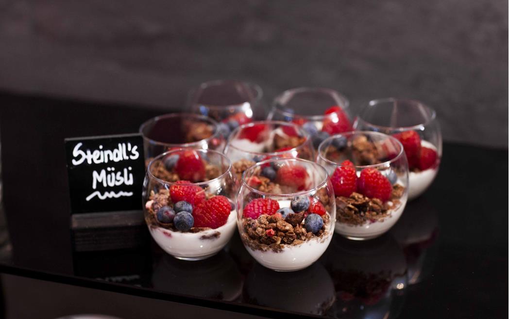Steindl's muesli in small glasses with yogurt, muesli and fresh fruit.