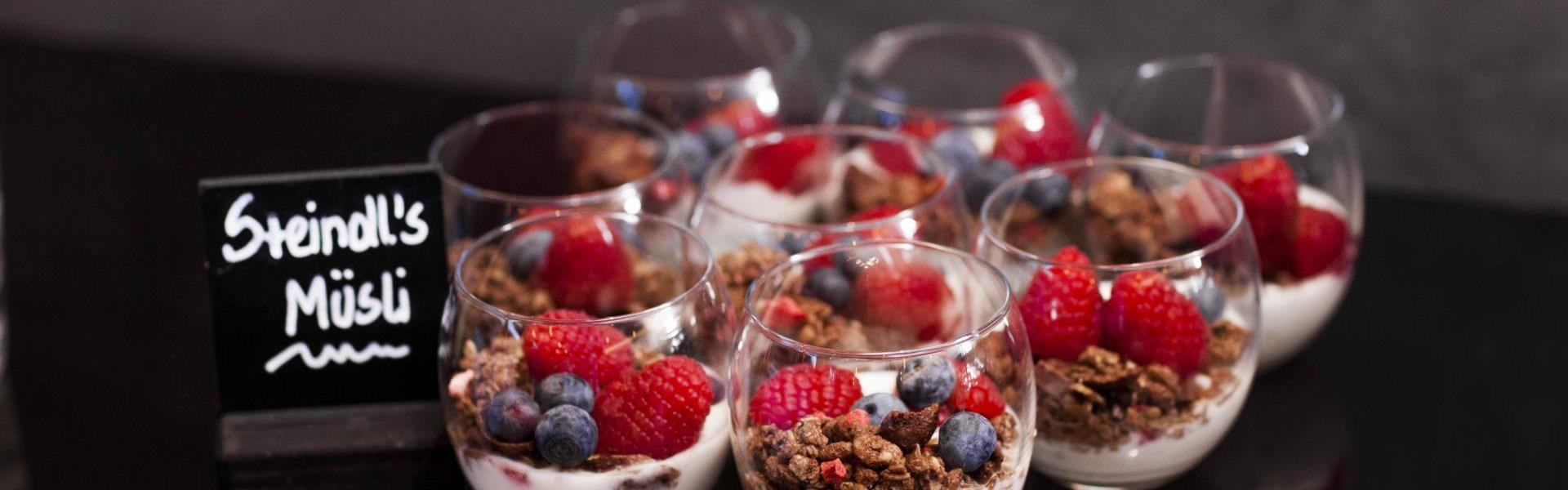 Steindl's muesli in small glasses with yogurt, muesli and fresh fruit.