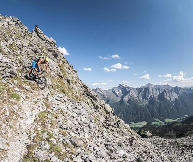 Tour Pfitscher Joch - Mountainbiker auf steinigem Bergpfad vor alpinem Panorama.