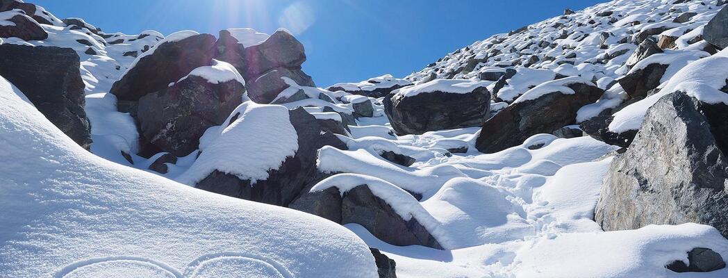 Heart in the snow in front of a snow-covered rocky landscape in the sunshine.