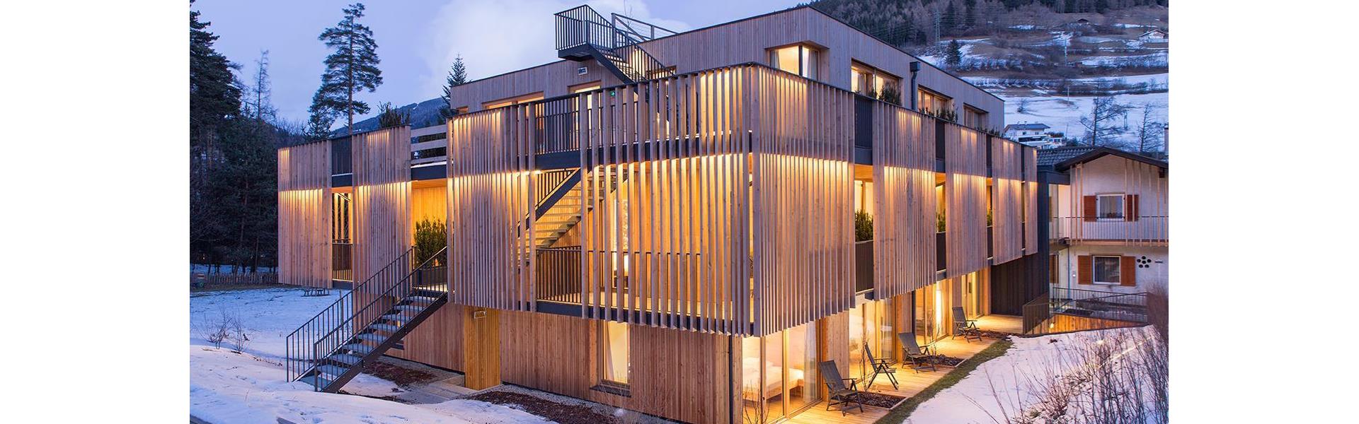 Steindl's Boutique Hotel con giardino innevato, architettura moderna in legno e bosco sullo sfondo.
