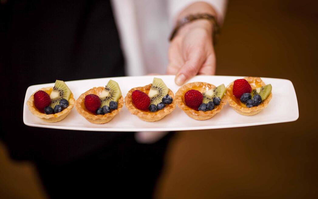 Diversi tortini con frutta su un piatto allungato.