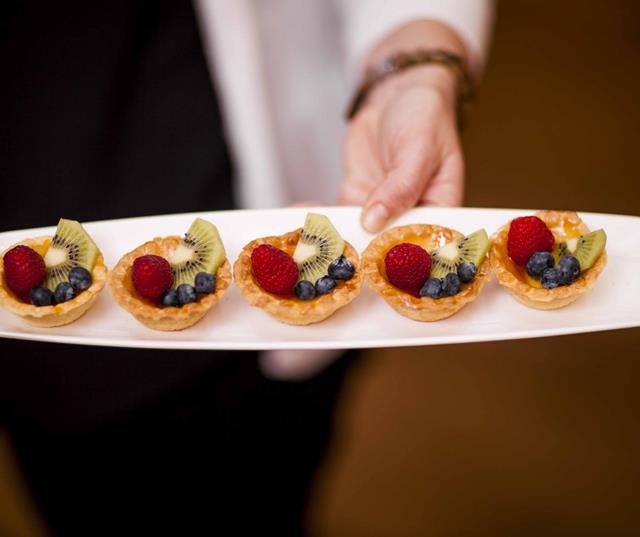 Several small fruit tarts on a long plate.