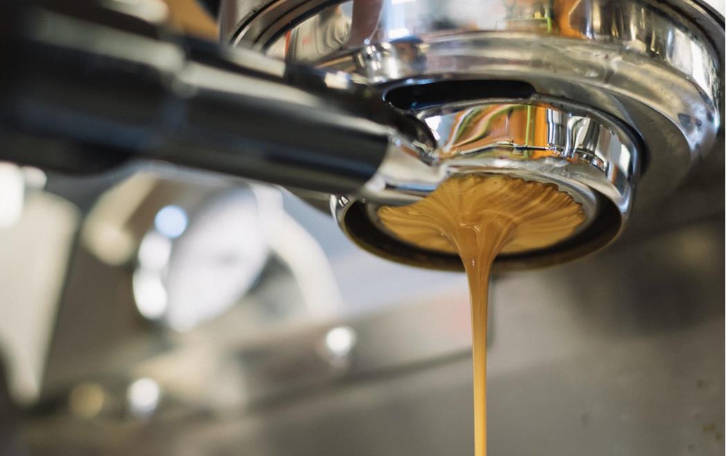Nahaufnahme eines Siebträgers, aus dem Kaffee läuft.