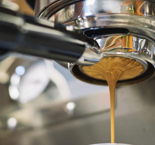 Nahaufnahme eines Siebträgers, aus dem Kaffee läuft.