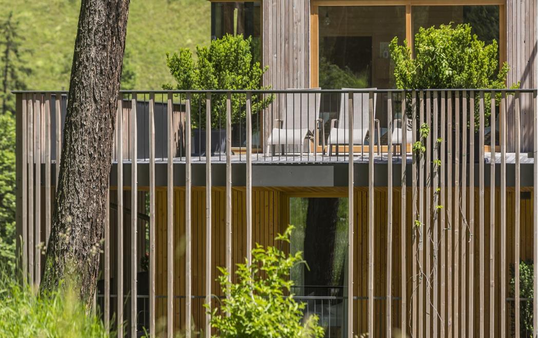 Wooden façade of Steindl's Boutique Hotel with a green terrace, seating and trees.