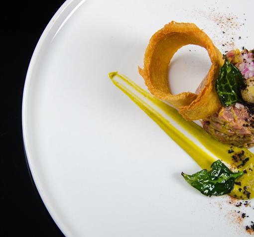 Tartar angerichtet auf einem weißen Teller mit gerösteter Brotscheibe und einem Wachtelei.