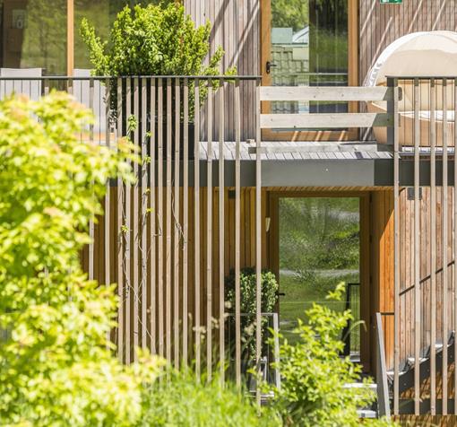 Modern exterior view of Steindl's Boutique Hotel with wooden details, balcony and green vegetation.