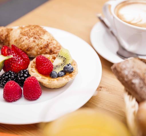Colazione dolce con brioche, torta e frutta fresca.