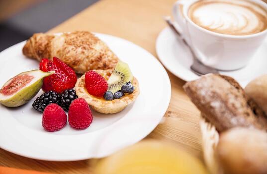 Süßes Frühstück mit Brioche, Kuchen und frischem Obst.