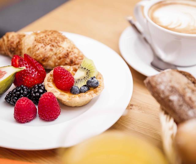 Colazione dolce con brioche, torta e frutta fresca.